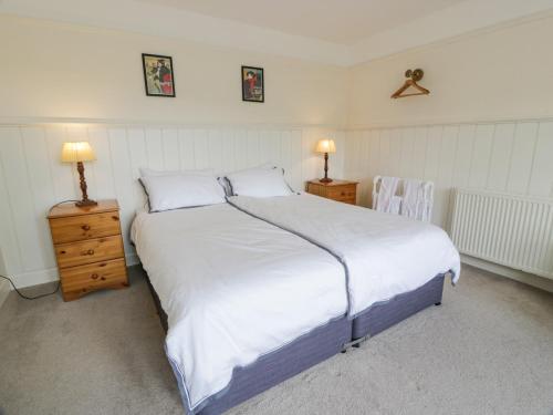 a bedroom with a large white bed with two tables and two lamps at High Auchenbrack in Thornhill