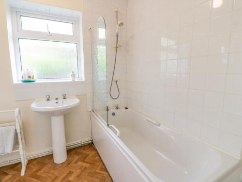 a white bathroom with a sink and a tub and a mirror at High Auchenbrack in Thornhill