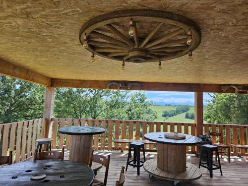 une terrasse couverte avec des tables et des chaises ainsi qu'une grande fenêtre dans l'établissement ferme de castel pouzouilh, à Le Fossat