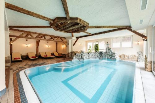 a large swimming pool in a hotel with chairs around it at Hotel Alpenkönigin in See
