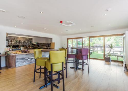 a kitchen with a bar with yellow and purple chairs at Loch Ness Highland Resort Pods in Fort Augustus