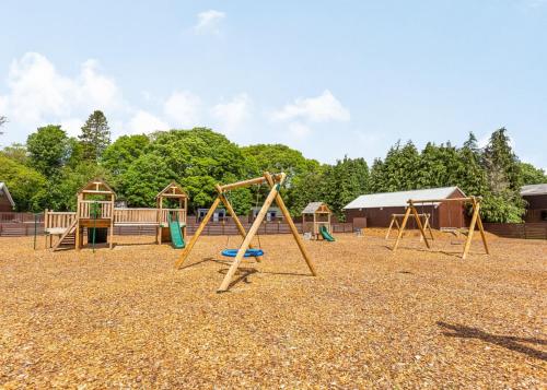 un parque infantil con 2 columpios y un columpio en Loch Ness Highland Resort Pods en Fort Augustus