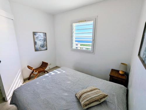 1 dormitorio con cama y ventana en Sunset Océan - appartement T2 avec vue imprenable sur l'océan et piscine en Saint-Gilles-les-Bains
