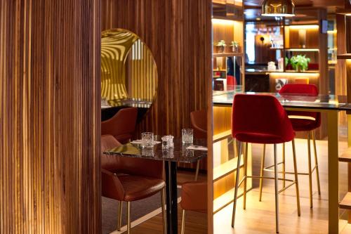 a bar in a restaurant with red stools at The Level at Melia White House in London