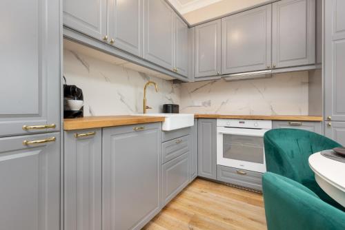 a kitchen with white cabinets and a green chair at Wola Beautiful Pet-Friendly Apartment by Renters in Warsaw