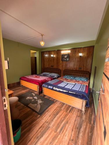 2 camas en una habitación con suelo de madera en Dik's Home en Darjeeling