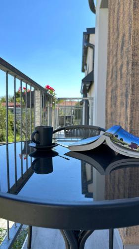 a table on a balcony with a coffee cup on it at Linden Apartman 107 GLAMOUR in Mosonmagyaróvár