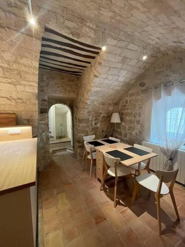 une salle à manger avec une table et des chaises et un mur en pierre dans l'établissement Maison de village, à Pernes-les-Fontaines