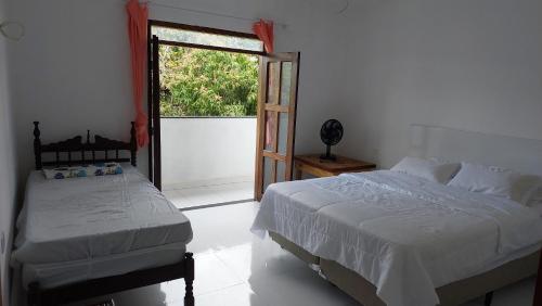 een slaapkamer met 2 bedden en een glazen schuifdeur bij Residencial Maria de Lourdes in Ibicoara