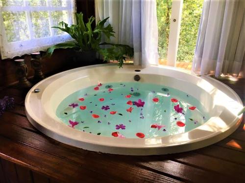 a large bath tub with flowers in it in front of a window at Cabana dos Sonhos na Serra SC in Rancho Queimado