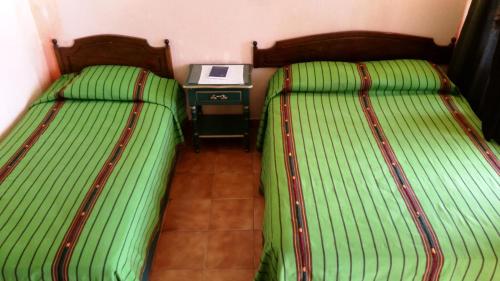 two beds in a room with a table with a laptop at Perla Maya Hotel in Panajachel