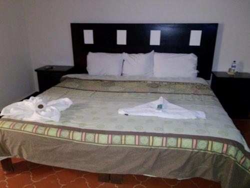 a bedroom with a bed with two towels on it at Hotel Posada del Cortijo in Morelia
