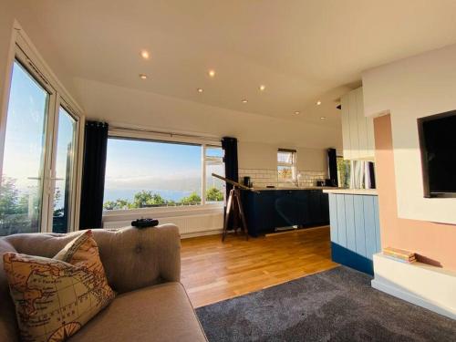 a living room with a couch and a large window at Polhawn Lookout, The Forgotten Chalet in Cawsand