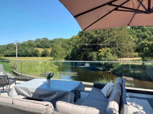 a patio with a couch and a table and a view of a river at Riverside Retreat in Llandysul