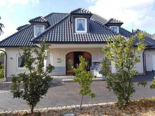 uma casa com telhado de azulejo e duas árvores em Ferienhaus Gesine 25193 em Bunde