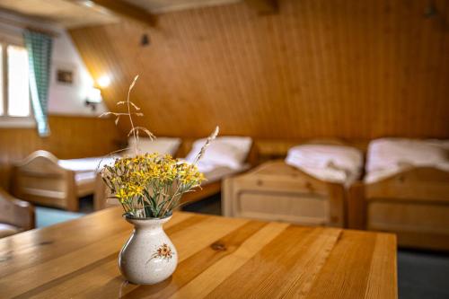 a vase with flowers sitting on a wooden table at Chata Zvoneček in Jiřetín pod Jedlovou