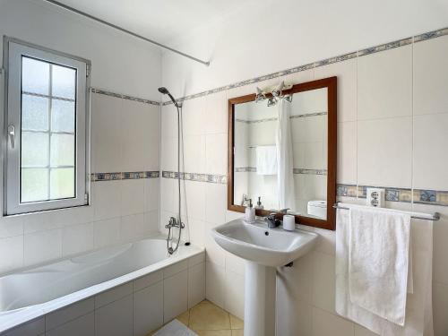 ein weißes Badezimmer mit einer Badewanne, einem Waschbecken und einem Badetubermott in der Unterkunft Sao Vicente Dual Haven by AH in São Vicente