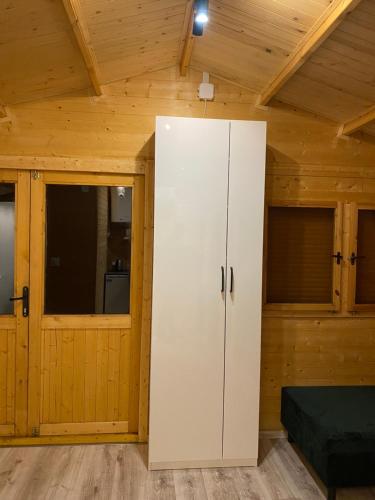 a large white cabinet in a room with wooden walls at Domek pod gwiazdami z jacuzzi in Brzozowa