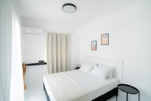 a white bedroom with a bed and a window at SyntheSeas Residence in Rethymno Town