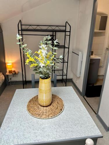 un vase jaune avec des fleurs sur une table dans l'établissement Studio proche Gare, à Bourg-en-Bresse