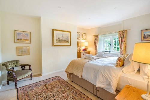 a bedroom with a bed and a chair and a window at Crumpet Cottage in Dorchester