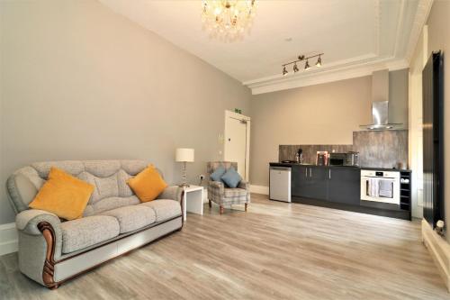 a living room with a couch and a kitchen at Signature - Linden House Flat 3 in Airdrie