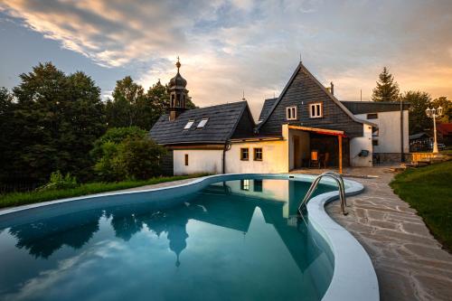 une maison avec une piscine en face d'une maison dans l'établissement Chata Zvoneček, à Jiřetín pod Jedlovou