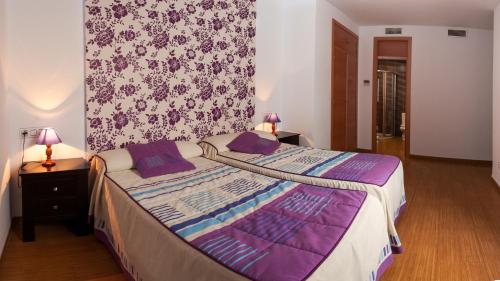 sypialnia z dużym łóżkiem z fioletowymi poduszkami w obiekcie Noriega w mieście Pozoblanco