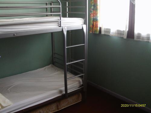Ce lit superposé se trouve dans un dortoir doté d'un mur vert. dans l'établissement torres, à Villecresnes