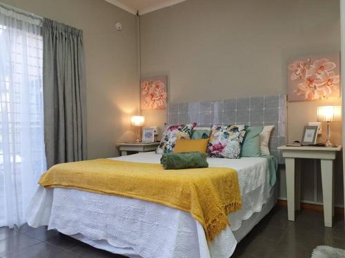a bedroom with a large bed with a yellow blanket at Tree Orchid in Polokwane
