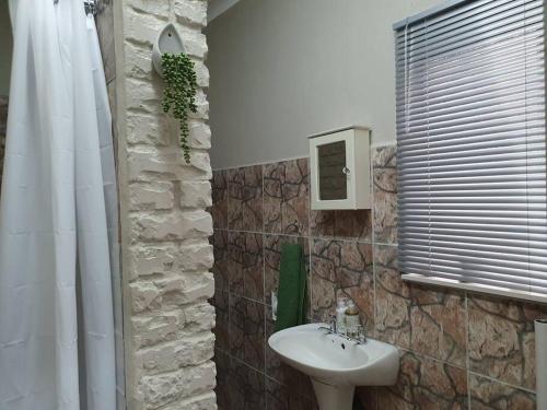 a bathroom with a white sink and a stone wall at Tree Orchid in Polokwane