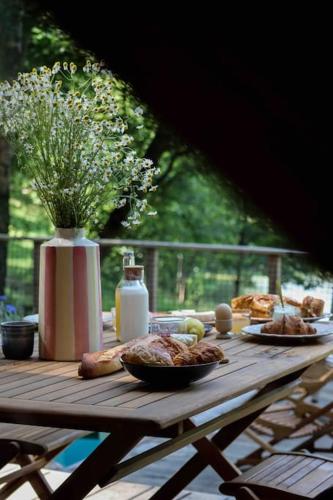 une table en bois avec de la nourriture et un vase de fleurs dans l'établissement Casa Moon & son bain nordique sur le lac, à Les Croix Chemins
