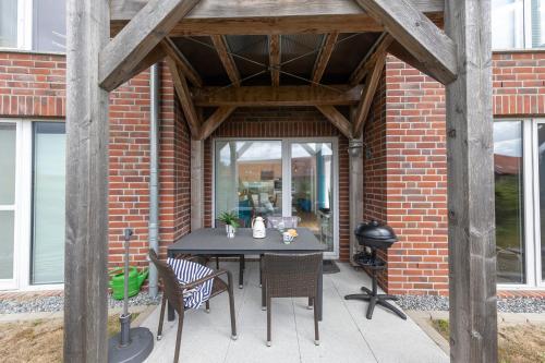 a patio with a table and chairs and a brick wall at LM 9-1-2 - Ferienwohnung Wremer Bogen Komfort in Schottwarden