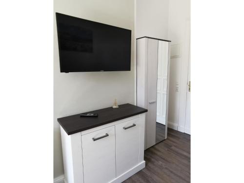 a room with a tv on a wall with a white cabinet at Ferienwohnung MeerZeit Villa Adler in Ahlbeck