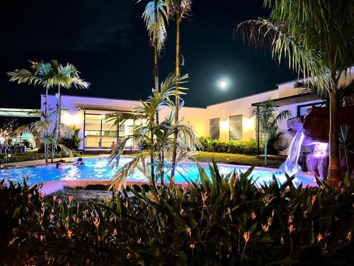 a swimming pool at night with palm trees and a building at QUINTA LA COLONIA in Restrepo