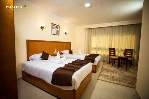 Palm Inn Suites Hotel في الغردقة: غرفة فندقية بسريرين وطاولة وكراسي