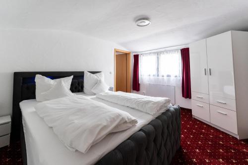 ein großes weißes Bett mit weißer Bettwäsche und Kissen in der Unterkunft Hotel Haus Biggen in Attendorn