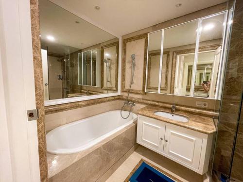 a bathroom with a tub and a sink and a mirror at The Jewel of La Casa III in Surabaya