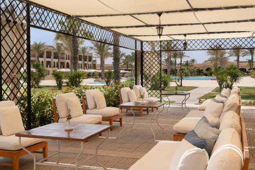 a patio with white chairs and tables and a pool at JAZ Oriental, Almaza Bay in Marsa Matruh
