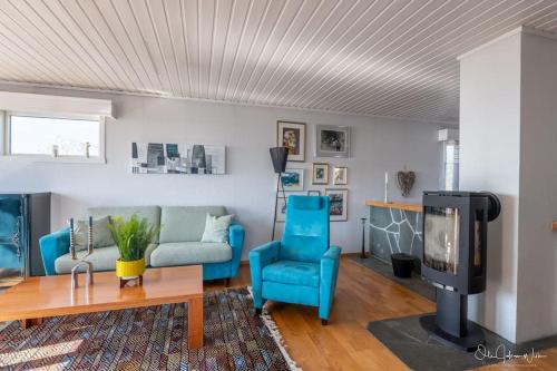 een woonkamer met blauwe stoelen en een tv bij Henningsvær, Lofoten with fantastic view in Henningsvær