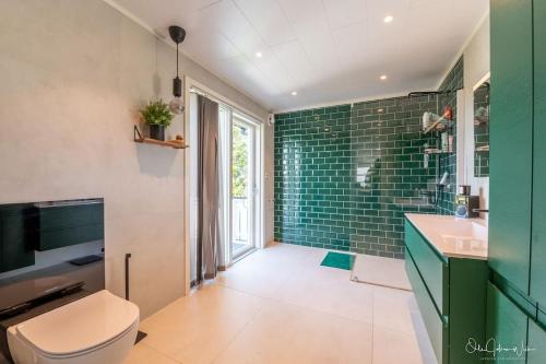 łazienka z toaletą i zielonymi płytkami metra w obiekcie Henningsvær, Lofoten with fantastic view w mieście Henningsvær