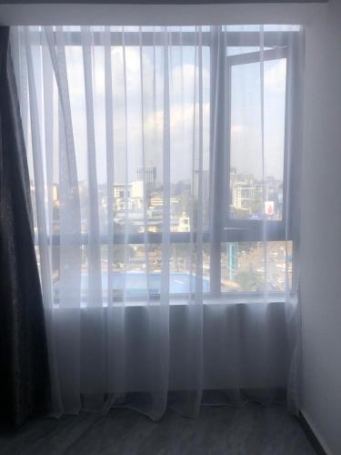 d'une fenêtre avec des rideaux blancs et une vue sur la ville. dans l'établissement Staroot residency Nairobi, à Nairobi