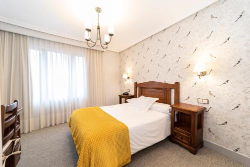 a hotel room with a bed with a yellow blanket at Hotel Restaurante De Torres in Felechosa