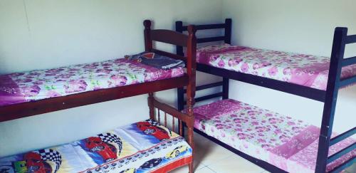 a room with three bunk beds in a room at Apartamento Praia Mongagua in Mongaguá