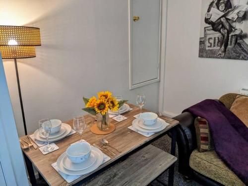 a table with plates and glasses and a vase of flowers on it at Hs UK Homes Beautiful 2 bed in Bradford in Bradford