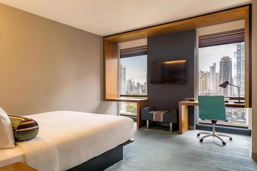 a hotel room with a bed and a desk and a chair at Aloft Panama in Panama City