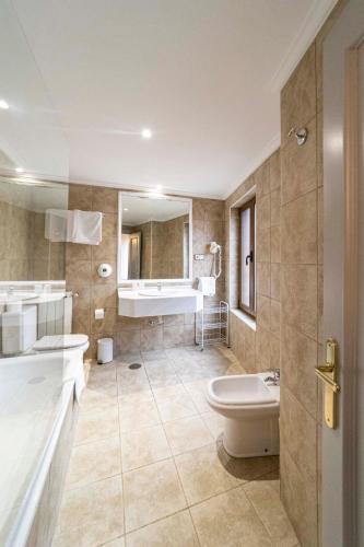 a bathroom with a tub and a toilet and a sink at Hotel Restaurante De Torres in Felechosa