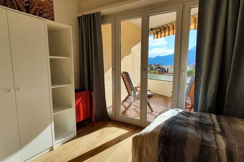 een slaapkamer met een deur naar een balkon met een stoel bij Apartment via San Carlo in Muralto-Locarno in Muralto