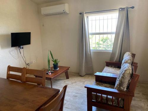 ein Wohnzimmer mit einem Sofa, einem Tisch und einem Fenster in der Unterkunft SkylineSuites Lost in Paradise - FA3 in Grand Anse