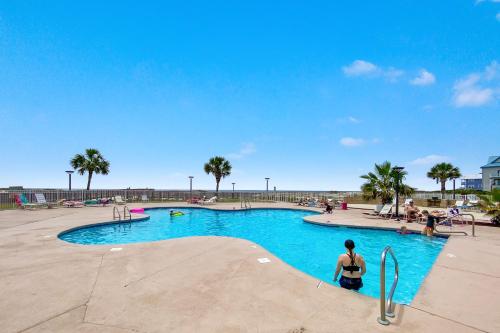a woman standing in front of a swimming pool at the beach at Beach Please condo 2 bedroom 2 bath sleeps 6 in Gulf Shores